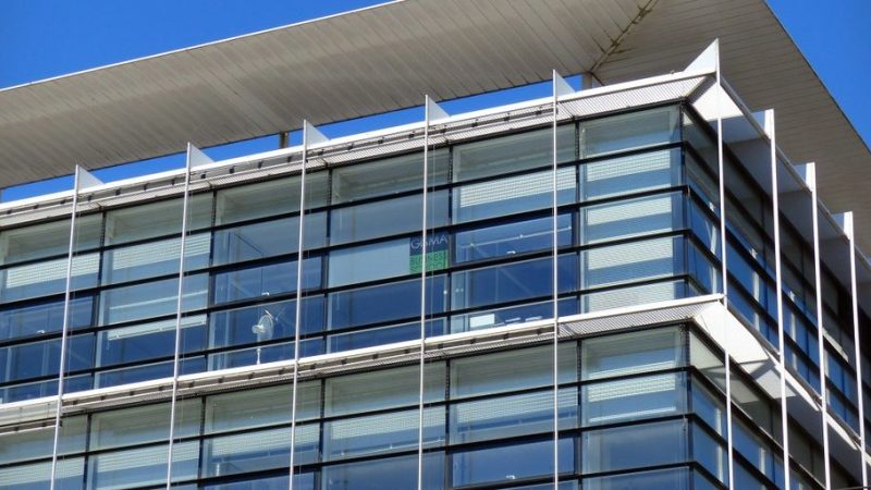 professional window cleaner on a ladder cleaning large glass windows of a modern building